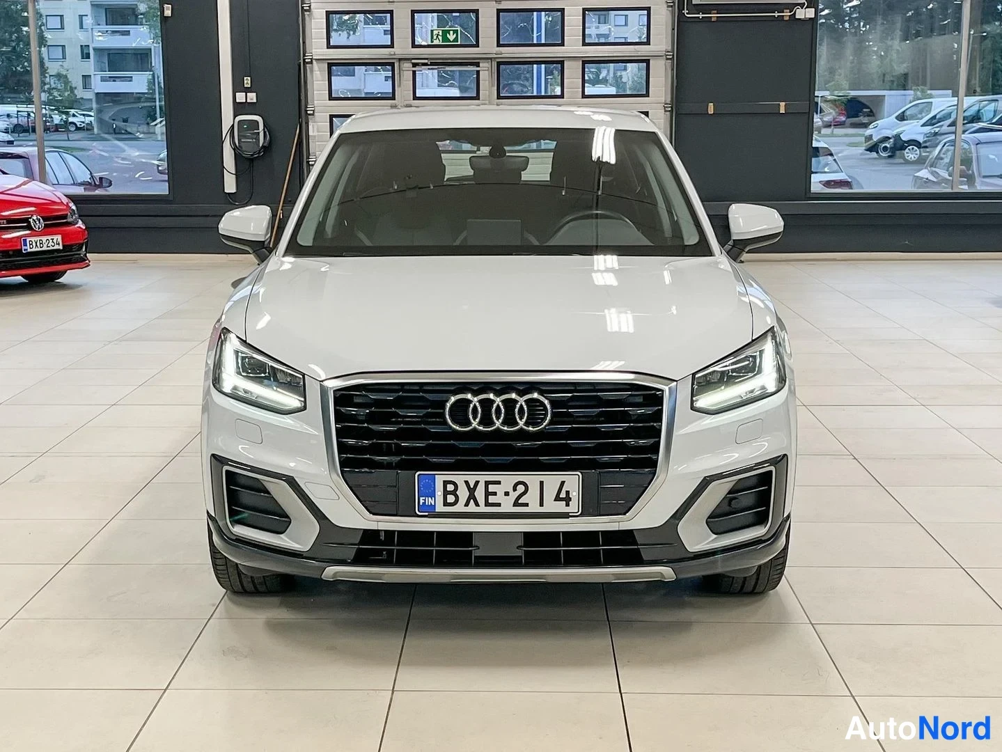 Edestä: Audi Q2:n etunäkyväsä valkoinen auto näyttää etumoottoritilan ja etusuojuksen, etulogo.