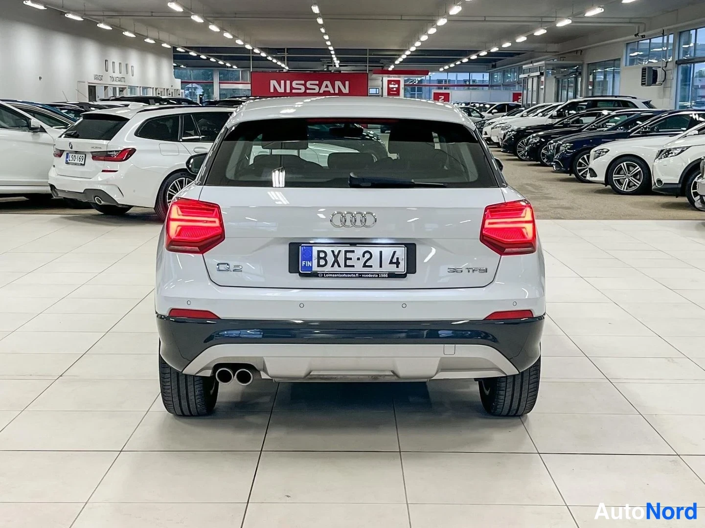 Takaa: Audi Q2:n takapää suoraan takaa valokuvattuna autosalissa; rekisterikilpi, AABB-merkki ja Q2-merkintä näkyvät.