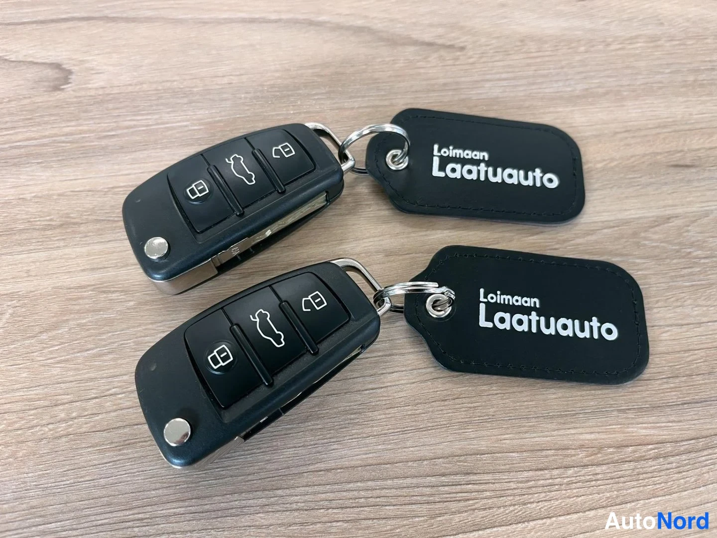 Muu: Kaksi Audi-avainpaneelia ja kaksi 'Loimaan Laatuauto'-avainlomia puupöydällä.