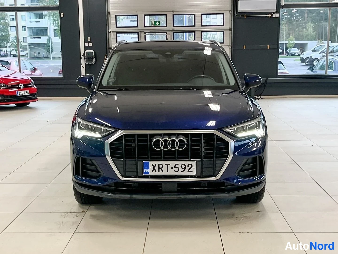 Edestä: Sinisen musta Audi Q3 edestä kuvattuna sisätiloissa, rekisterikilpi.