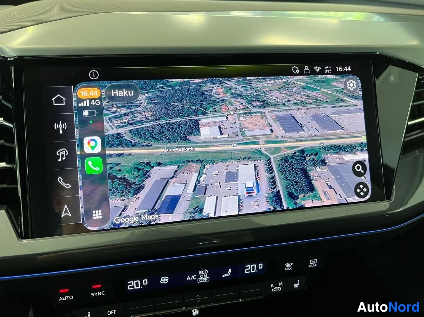 Yksityiskohta: Keskikonsolin suuri infotainment-näyttö, jolla on käynnissä Google Maps -karttanäkymä satelliittikuvana; näytön reunassa Apple CarPlayn sovelluskuvakkeet ja sta