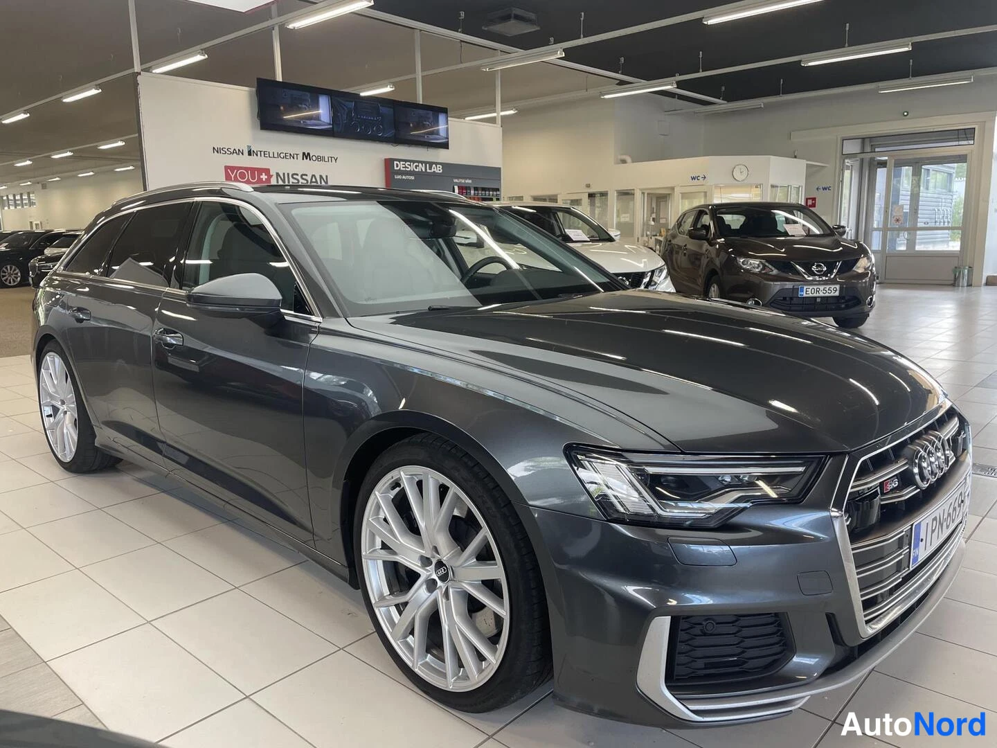 Etuviisto, nokka oikealle: Audi S6 Avant -farmari autokaupan näyttelytilassa, keulakolmasosakulma oikealta, tummanharmaa maalaus.
