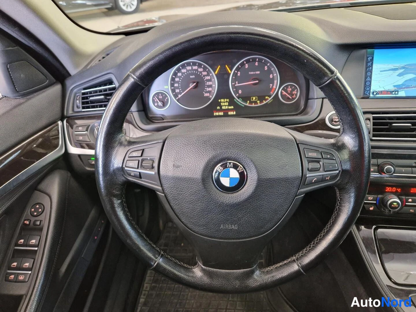 Muu: BMW-ohjauspyörä ja mittaristo lähikuvassa, kojelaudan näyttö osittain näkyvillä.