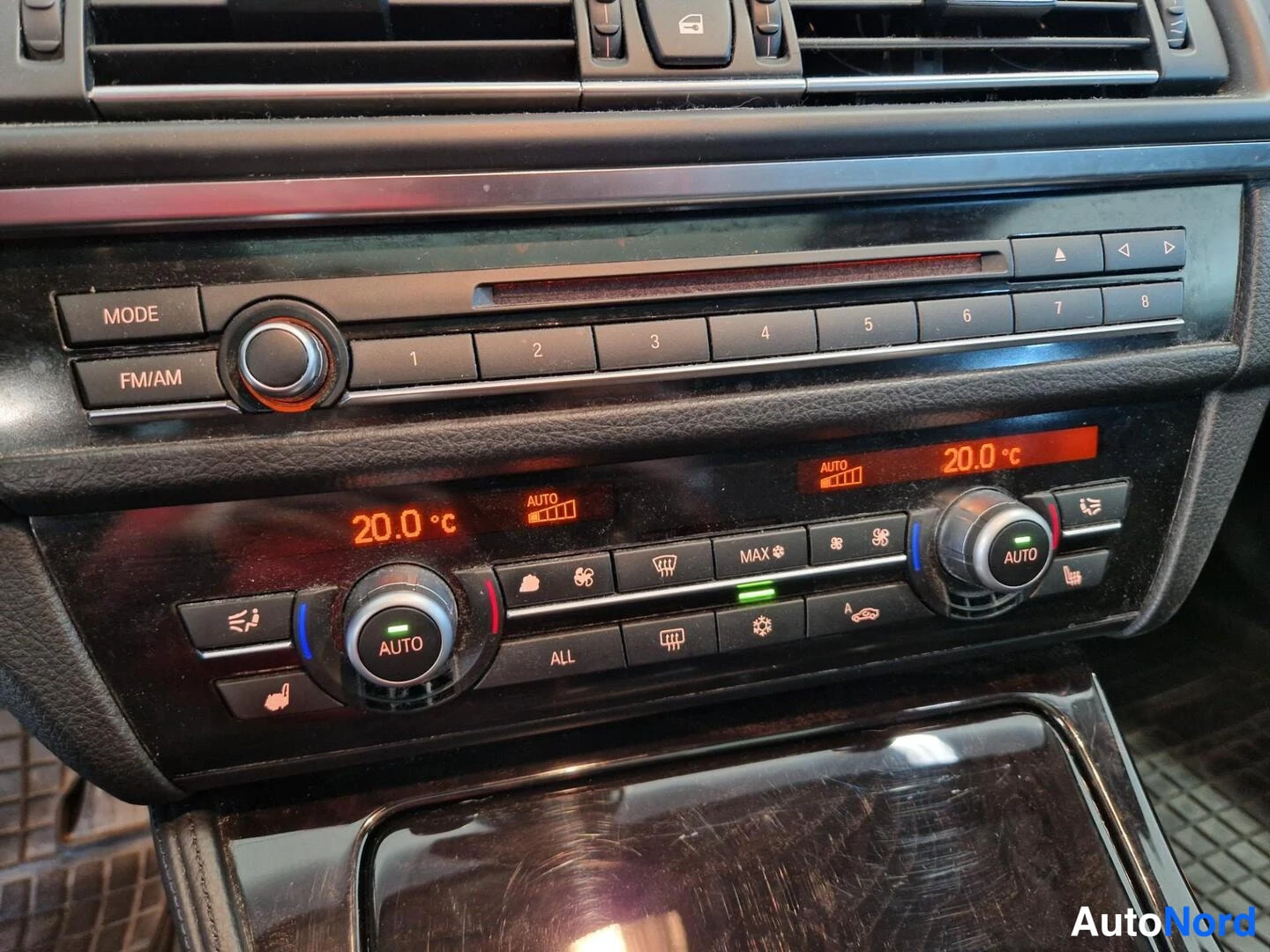 Muu: Keskinäisen konsolin äänentoisto- ja ilmastointipaneeli, näytössä 20,0 °C ja AUTO-asetukset.
