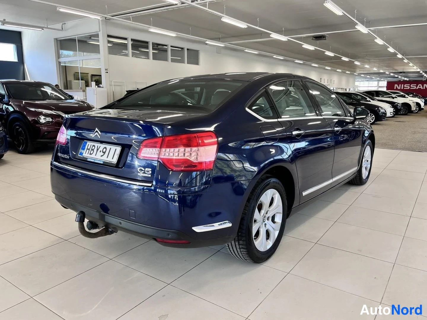 Takaviisto: Tummansininen Citroën C5 -sedan takaa sivulta; rekisteri, lukittu vetokoukku näkyvissä.