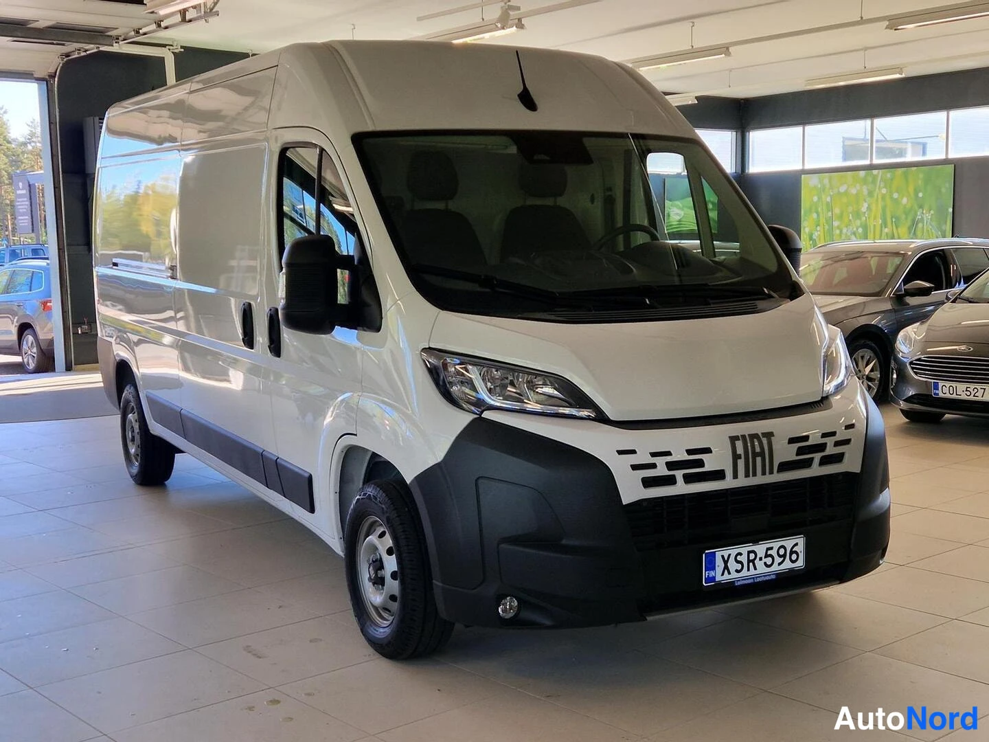 Etuviisto, nokka oikealle: Fiat Ducato -pakettiauto etuviistöstä oikealta, valkoinen korimalli autonhallissa.