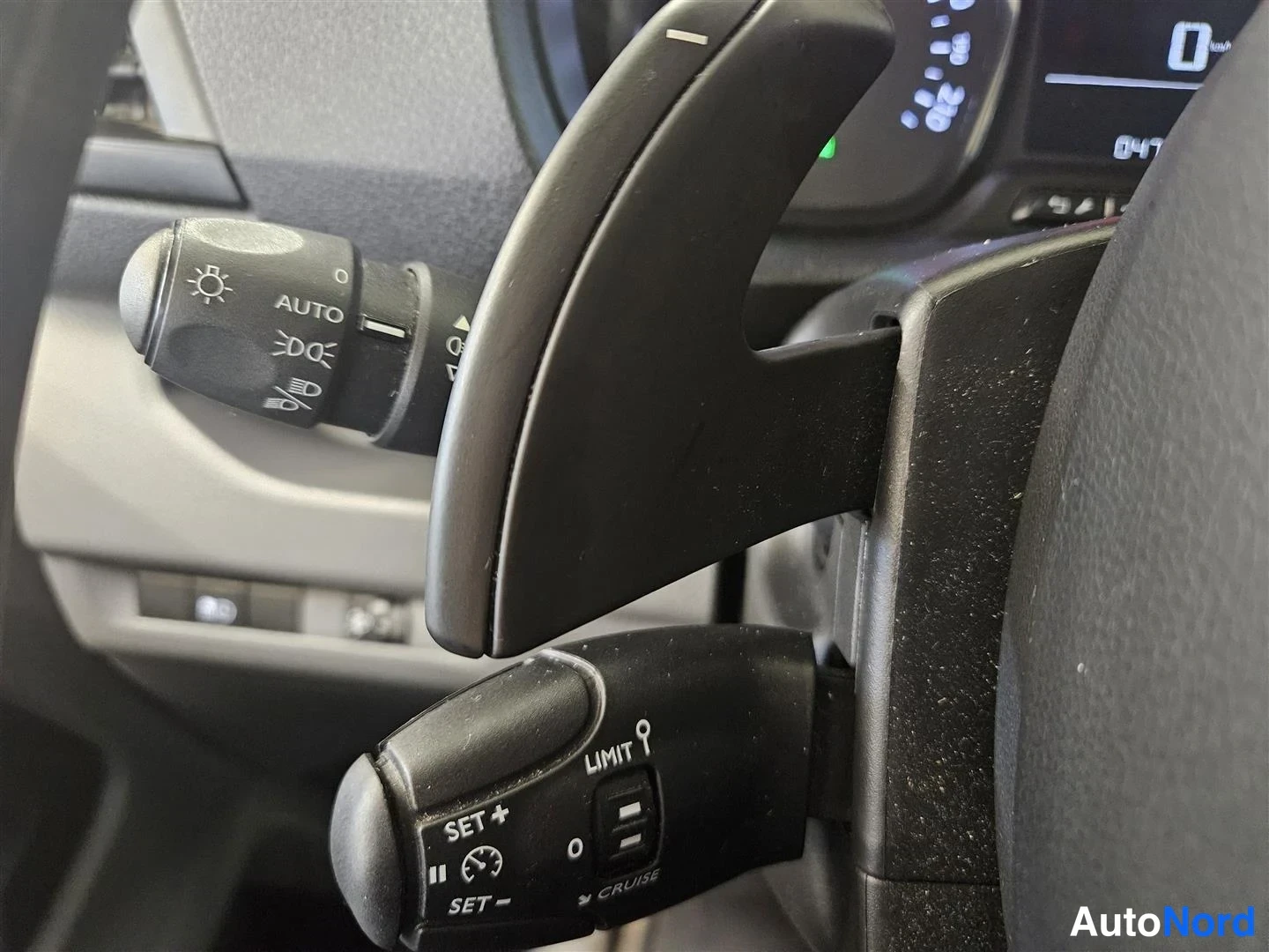 Edestä: Ajovalokytkin AUTO-merkinnällä ja cruise-pidine ohjauspyörän takana.