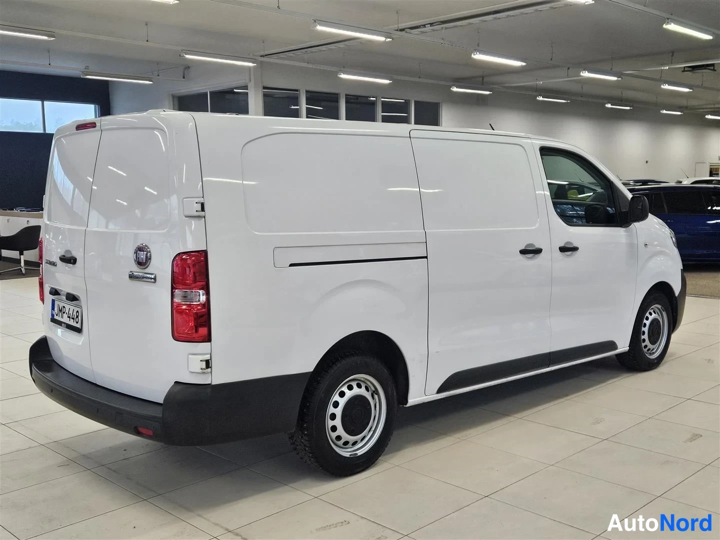 Takaviisto: Fiat Scudo -pakettiauton takakulma vasemmalta valkoisena autohallissa, rekisteritunnus.