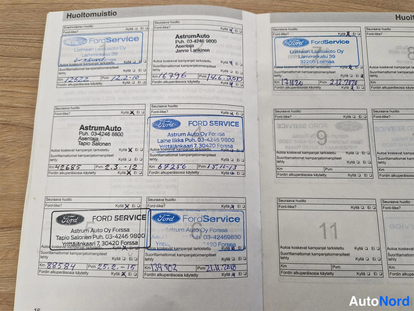 Yksityiskohta: Auki avattu huoltokirja (Huoltomuistio), jossa useita Ford Service -leimoja ja käsin kirjoitettuja huoltomerkintöjä.