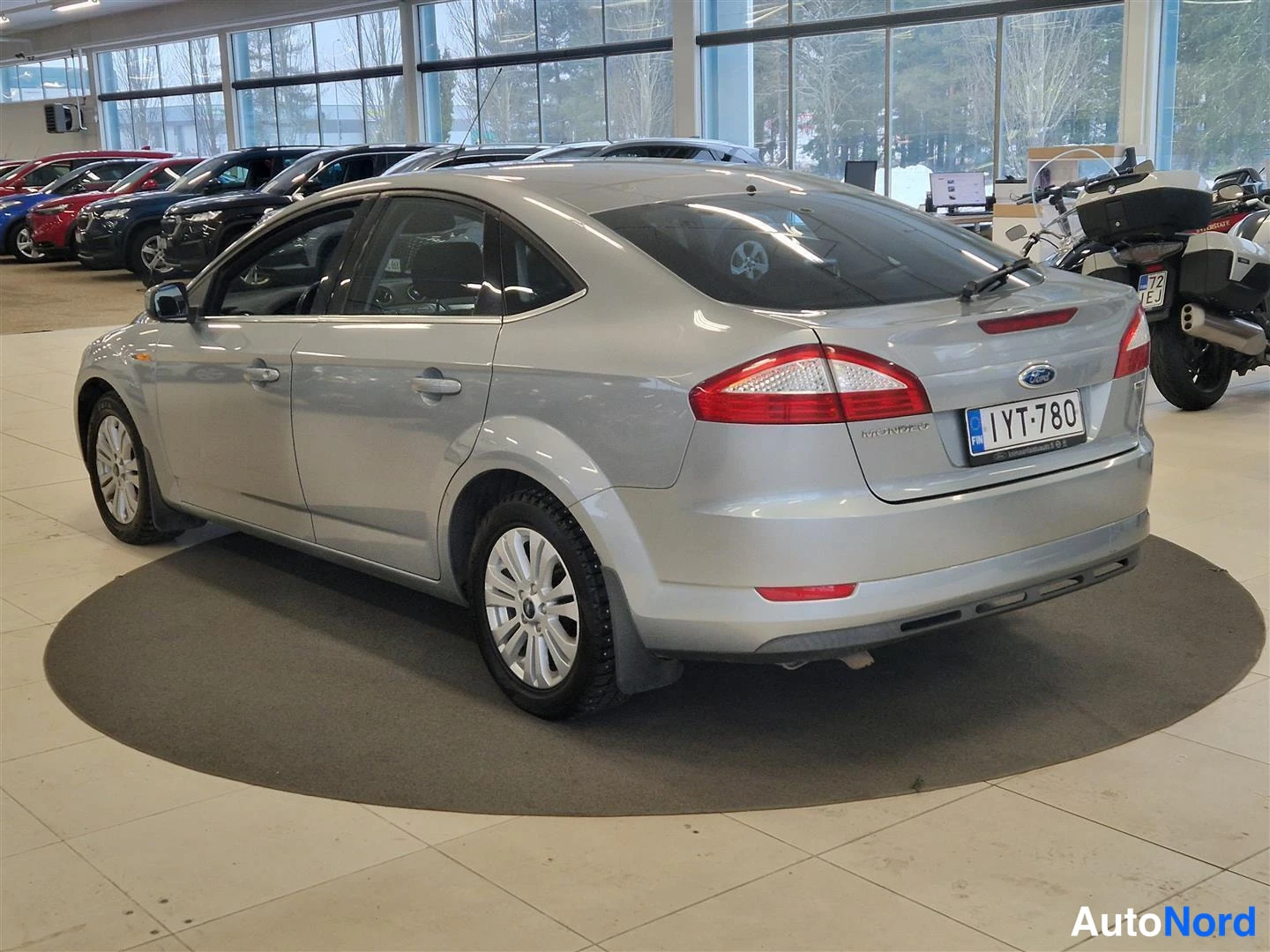 Takaviisto: Hopeanvärinen Ford Mondeo -henkilöauto takakulmanäkymä oikealta; takavalot, Mondeo-merkintä ja -rekisterikilpi näkyvät.