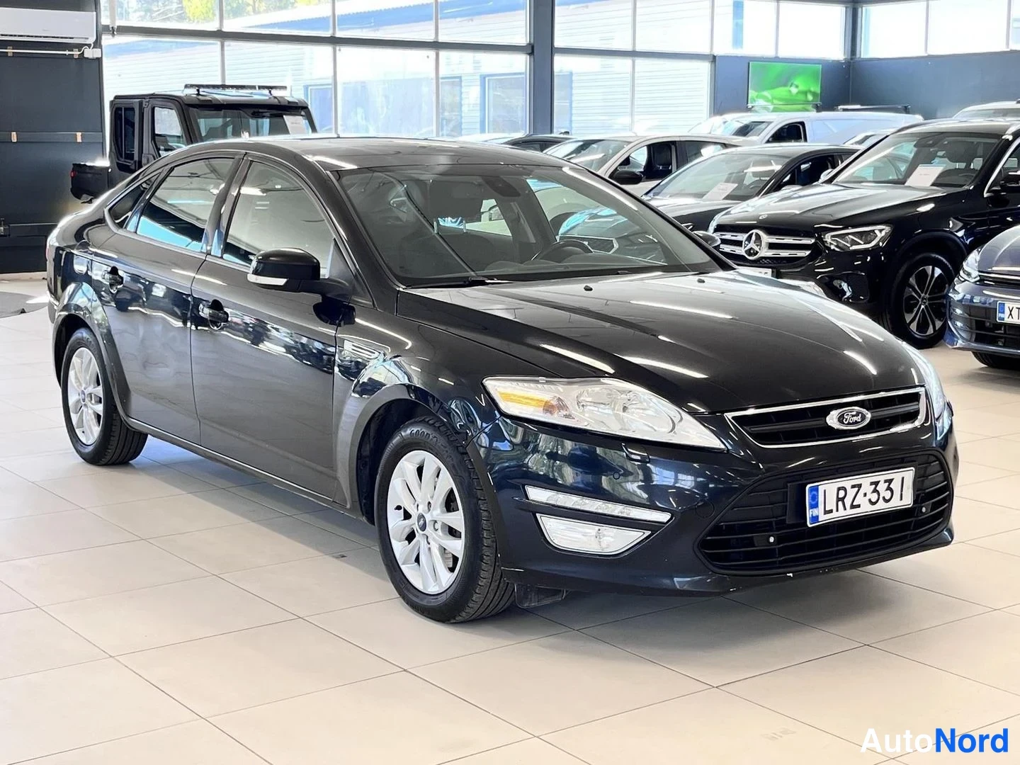 Etuviisto, nokka oikealle: Musta Ford Mondeo -sedan oikealta etukulmasta kuvattuna autonmyyntihallissa.