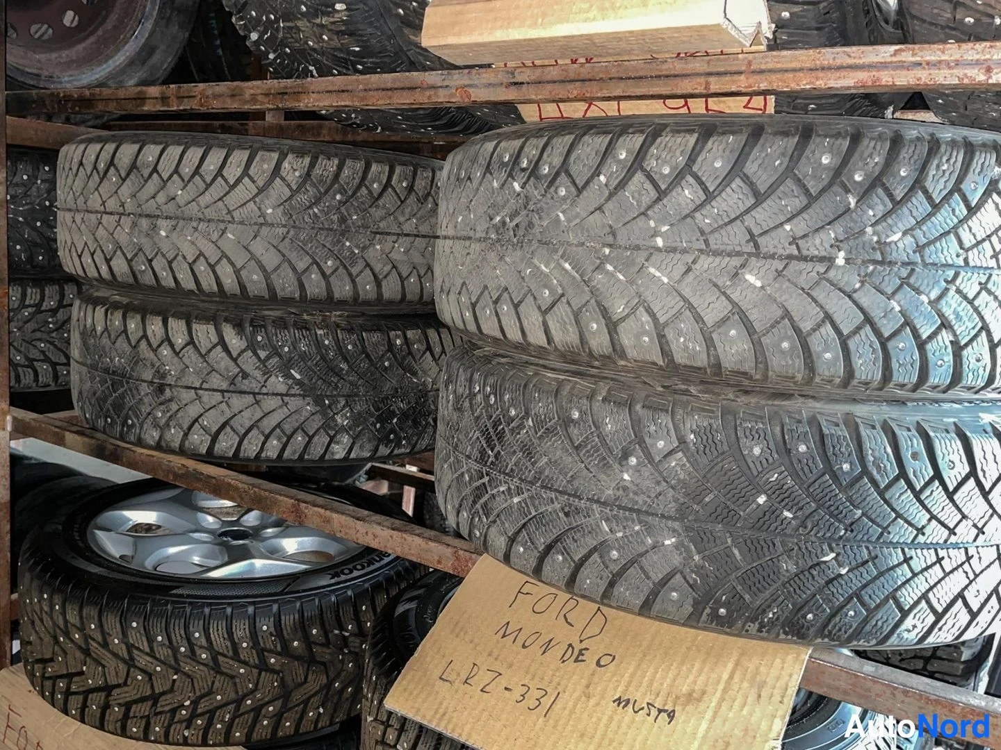 Muu: Telineessä riippuvat neljä nastarengasta, alhaalla pahvilappu, johon on käsin kirjoitettu FORD MONDEO MUSTA.