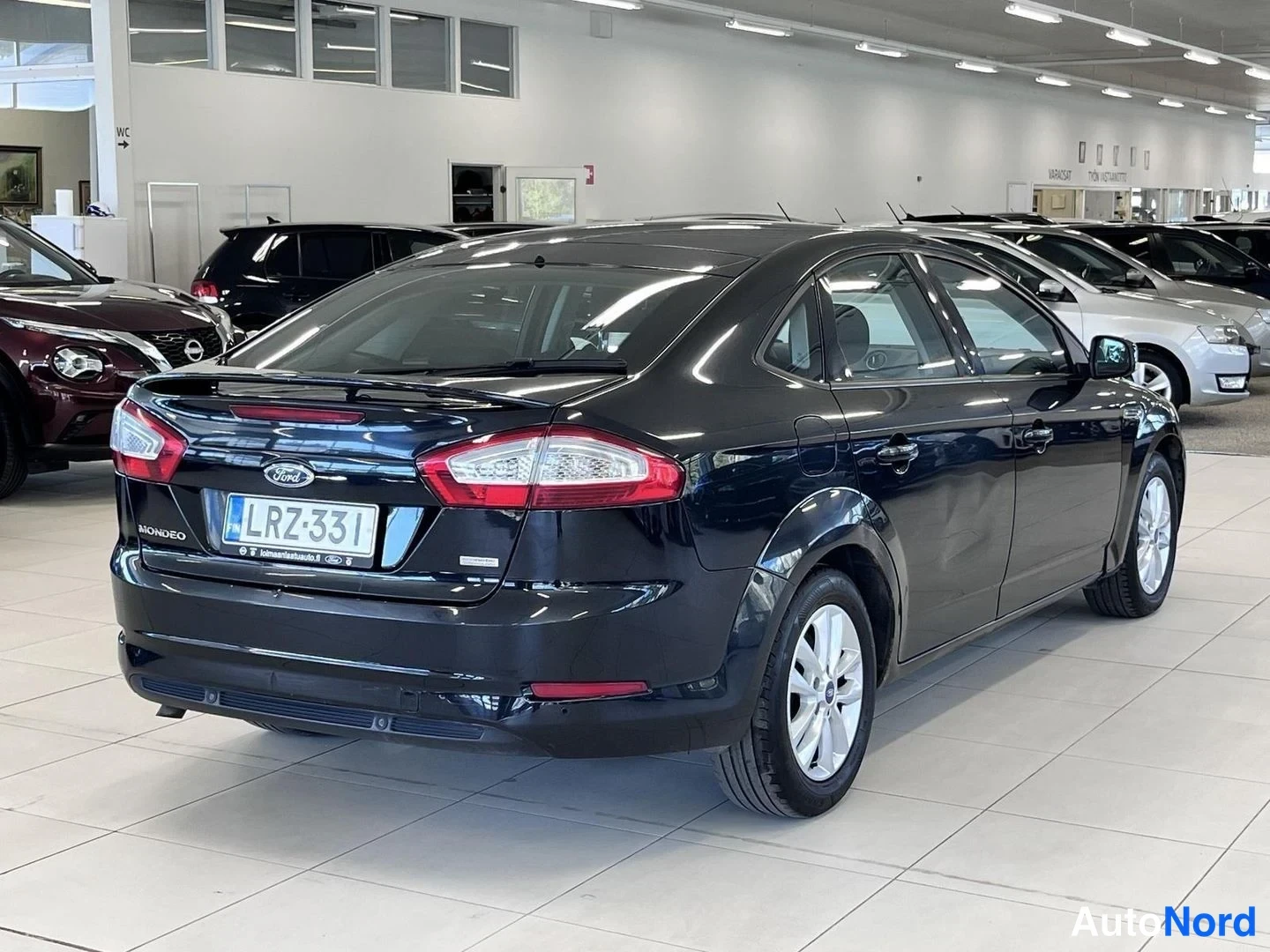 Takaviisto: Mustan Ford Mondeo -sedanin takaosa ja vasen kylki autonäyttelyn lattialla.