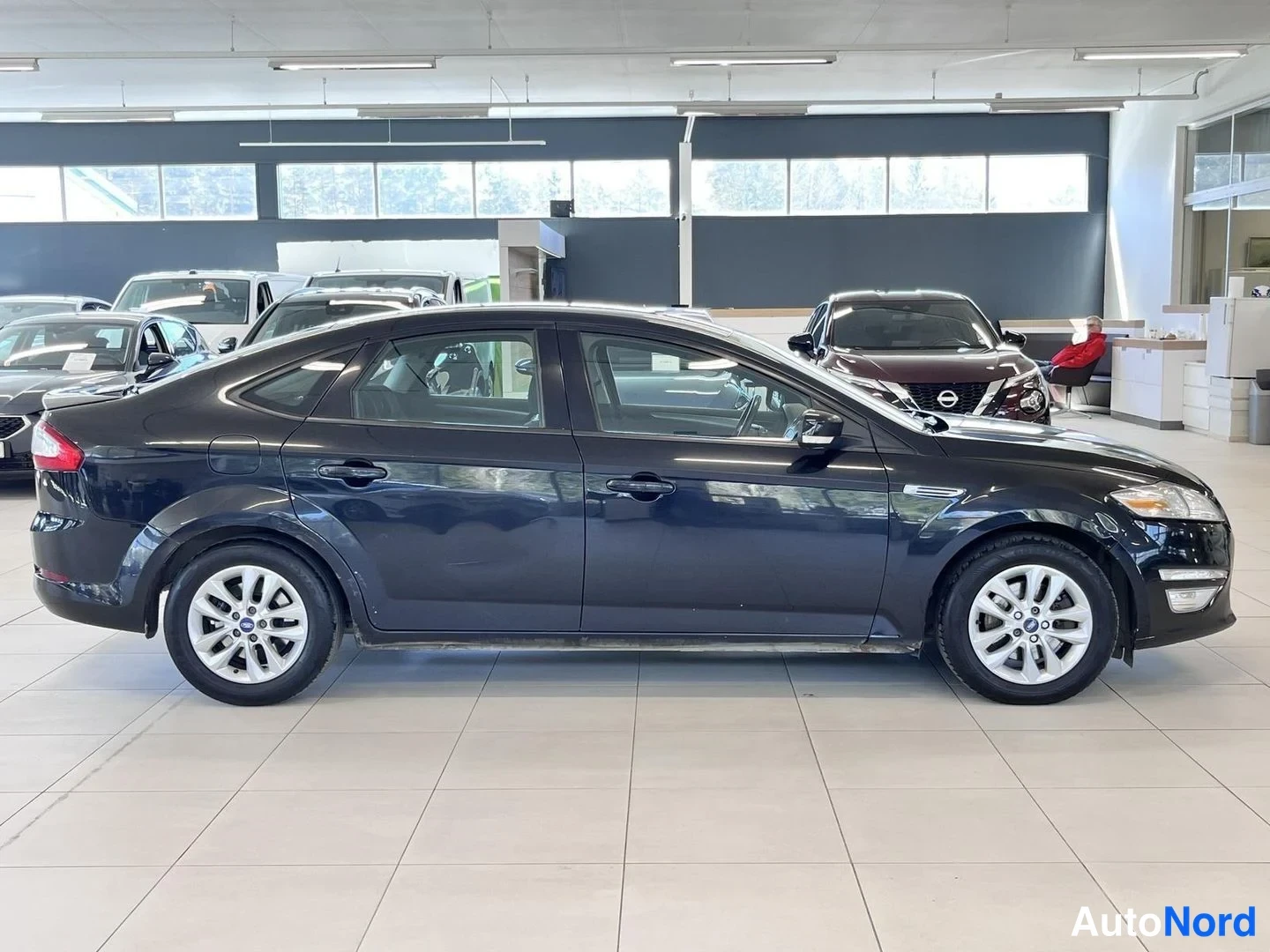 Etuviisto, nokka oikealle: Mustan Ford Mondeon etuosa ja oikea kylki autonäyttelyn lattialla.
