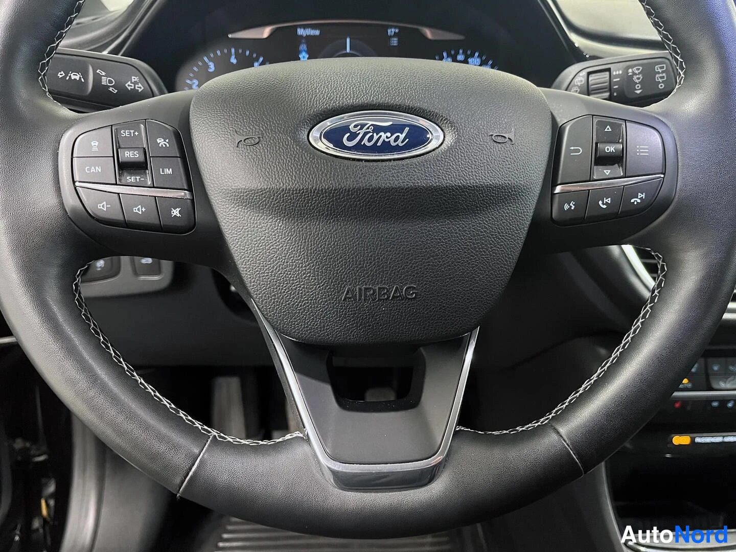 Muu: Ford-merkkinen ohjauspyörä, jossa AIRBAG-teksti ja monitoiminapit; taustalla kojelauta.