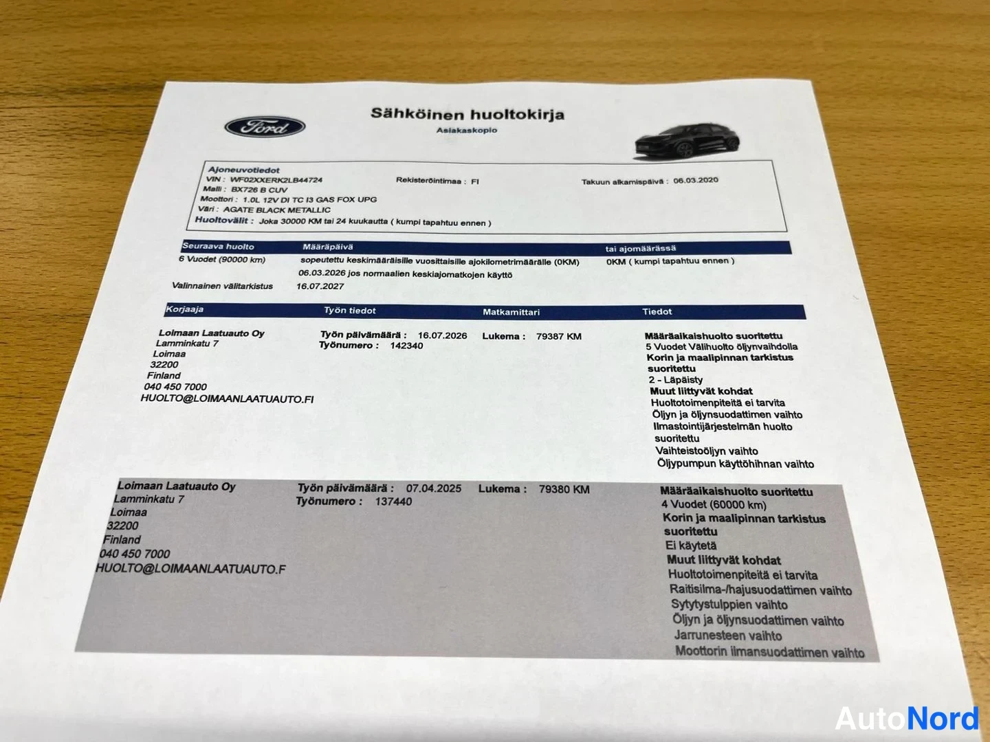 Yksityiskohta: Pöydällä paperille tulostettu Sähköinen huoltokirja -asiakirja: Ford B1258 1.0 EcoBoost, rekisteri, kaksi huoltomerkintää (79380 km / 07.04.2025 ja 79387 km / 1