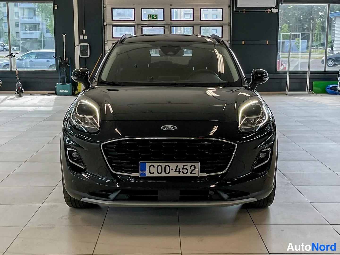 Edestä: Musta Ford Puma suoraan edestä, Ford-merkki ja.hexa-kaukosihtverkko etumoottoritilassa, rekisteritunnus C00-452.