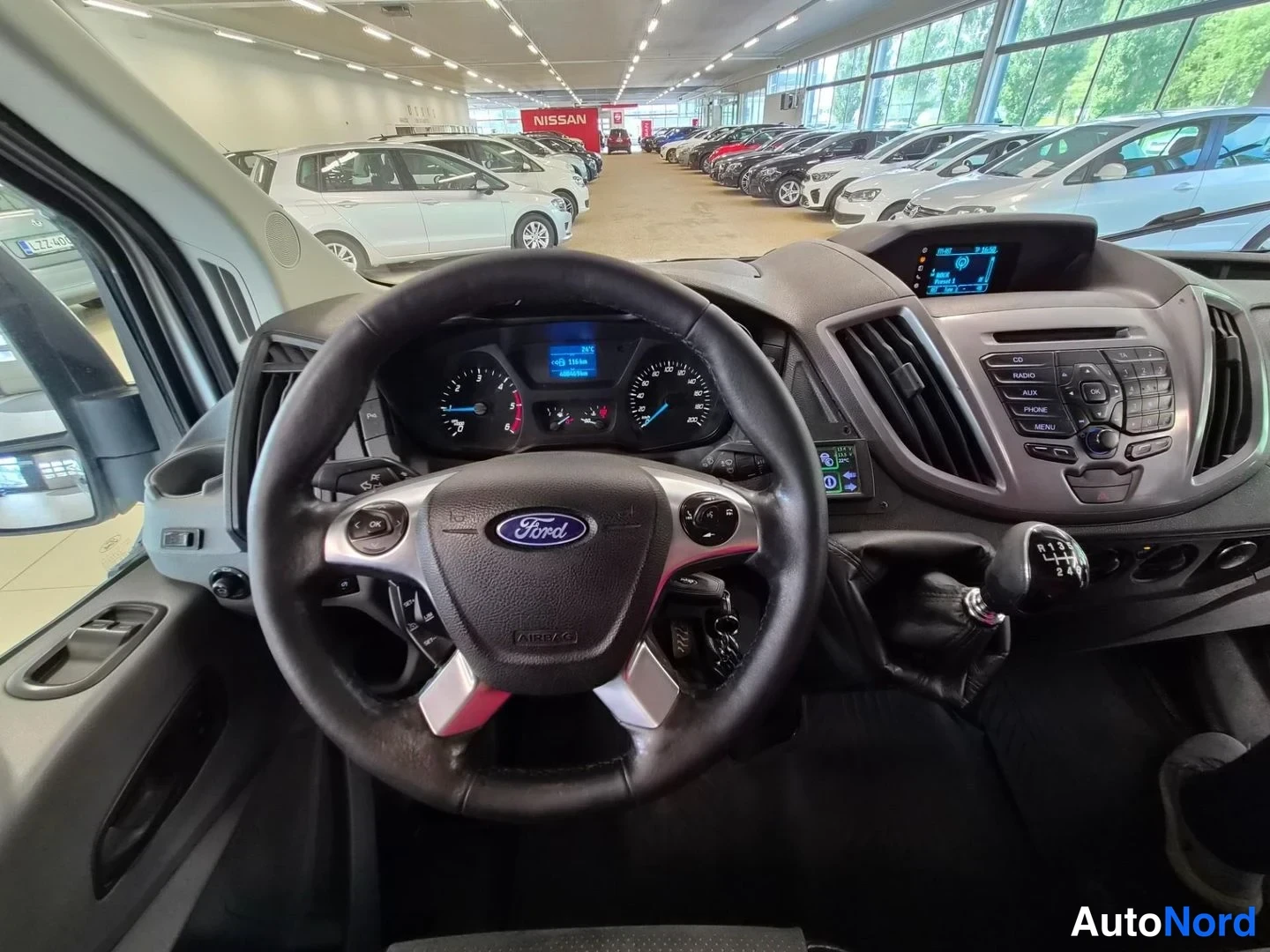Edestä: Kuljettajan paikalta kuvattu Ford-merkkinen ohjauspyörä, analogiset mittarit, keskikäyttöinen audio-/navigointipaneeli ja käsivalinta-vaihteenkeksi.