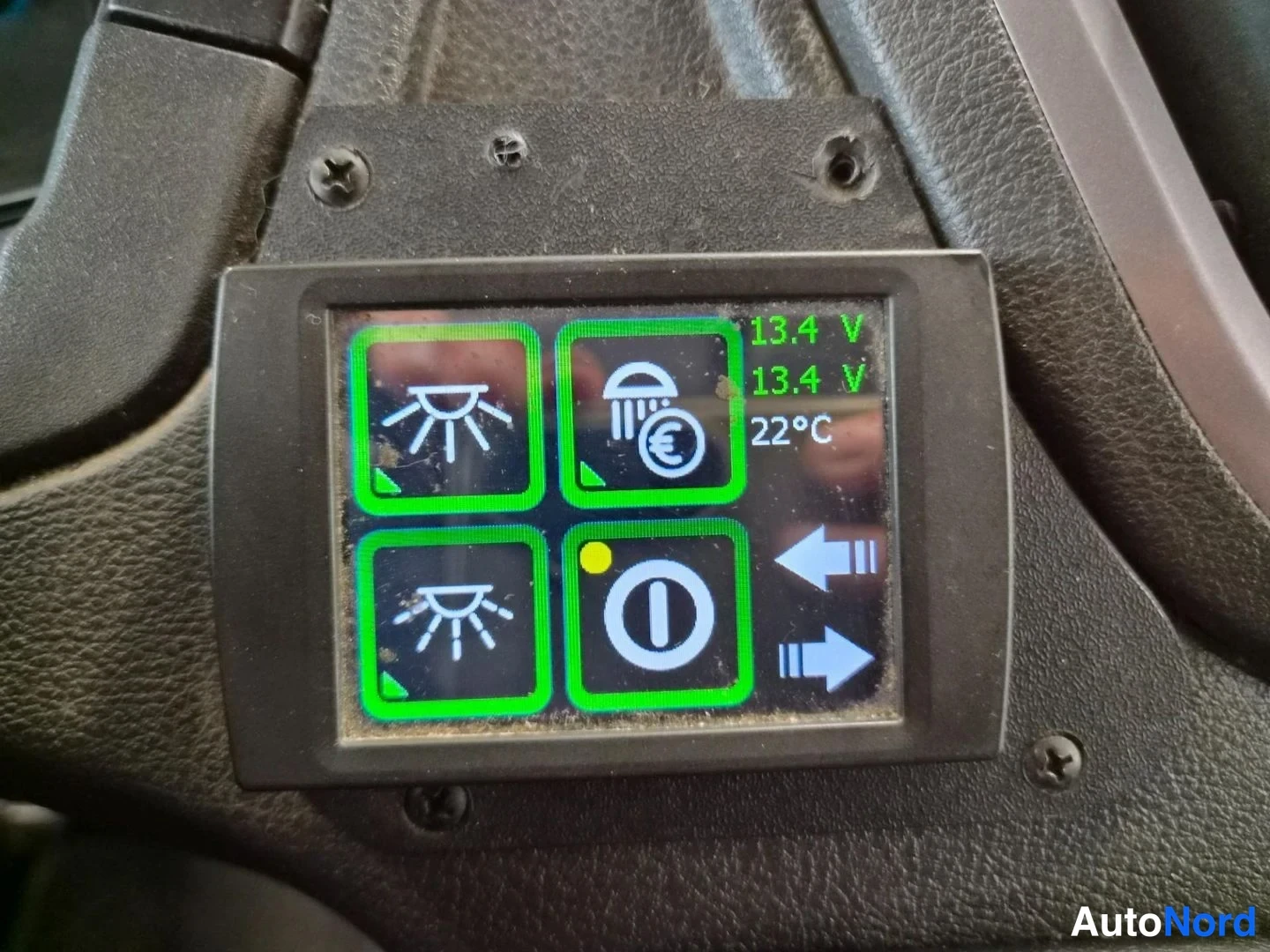 Yksityiskohta: Ohjauspölyssä kiinnitetty automaattilämmittimen kaukosäädin, jonka näytössä lukee 13,4 V kahdesti sekä 22°C, ja neljä kuvaketta