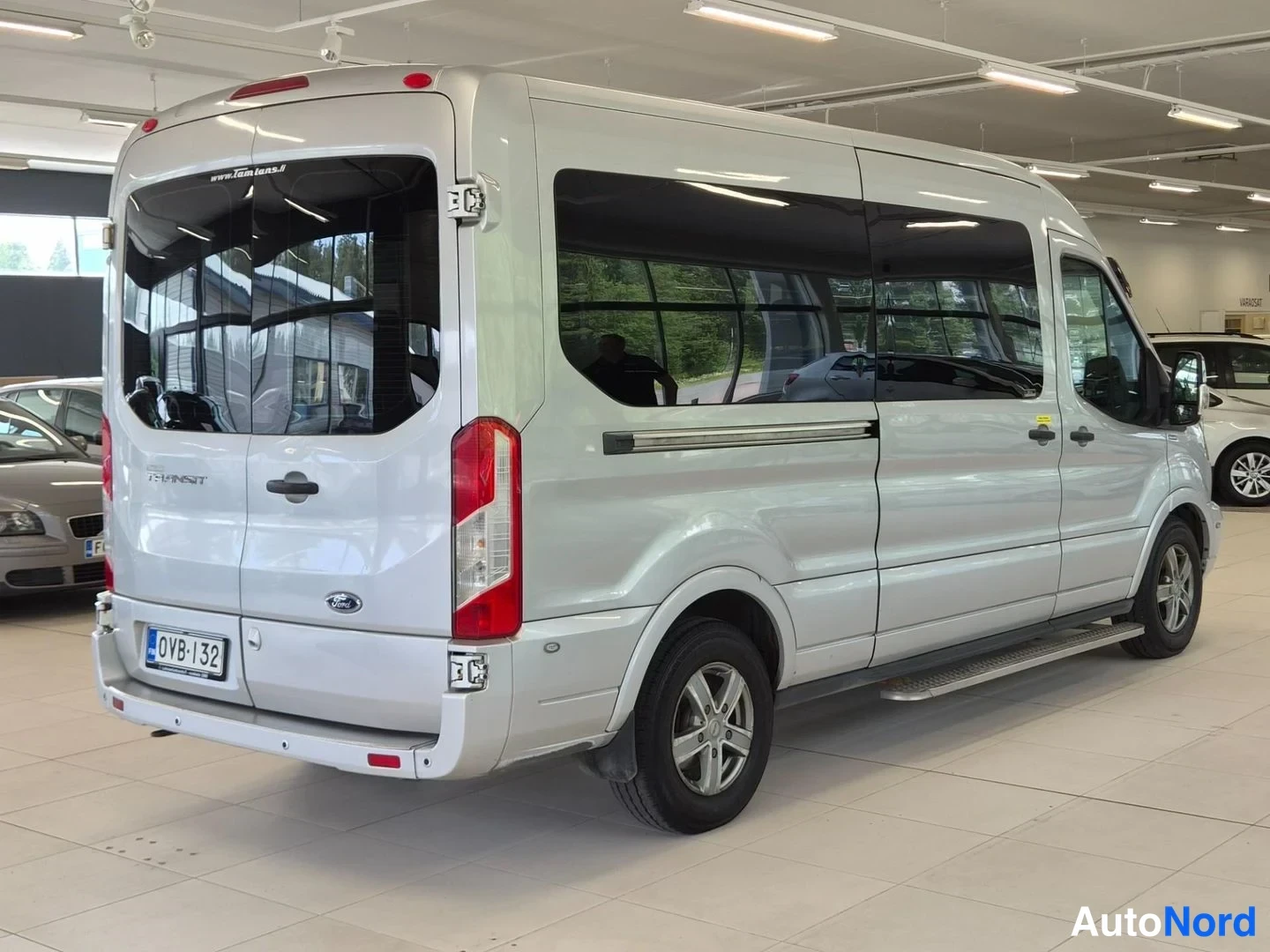 Takaviisto: Ford Transit -pakettiauton takaosa ja vasen kylki sisätiloissa, hopeinen koripinta, rekisterikilpi