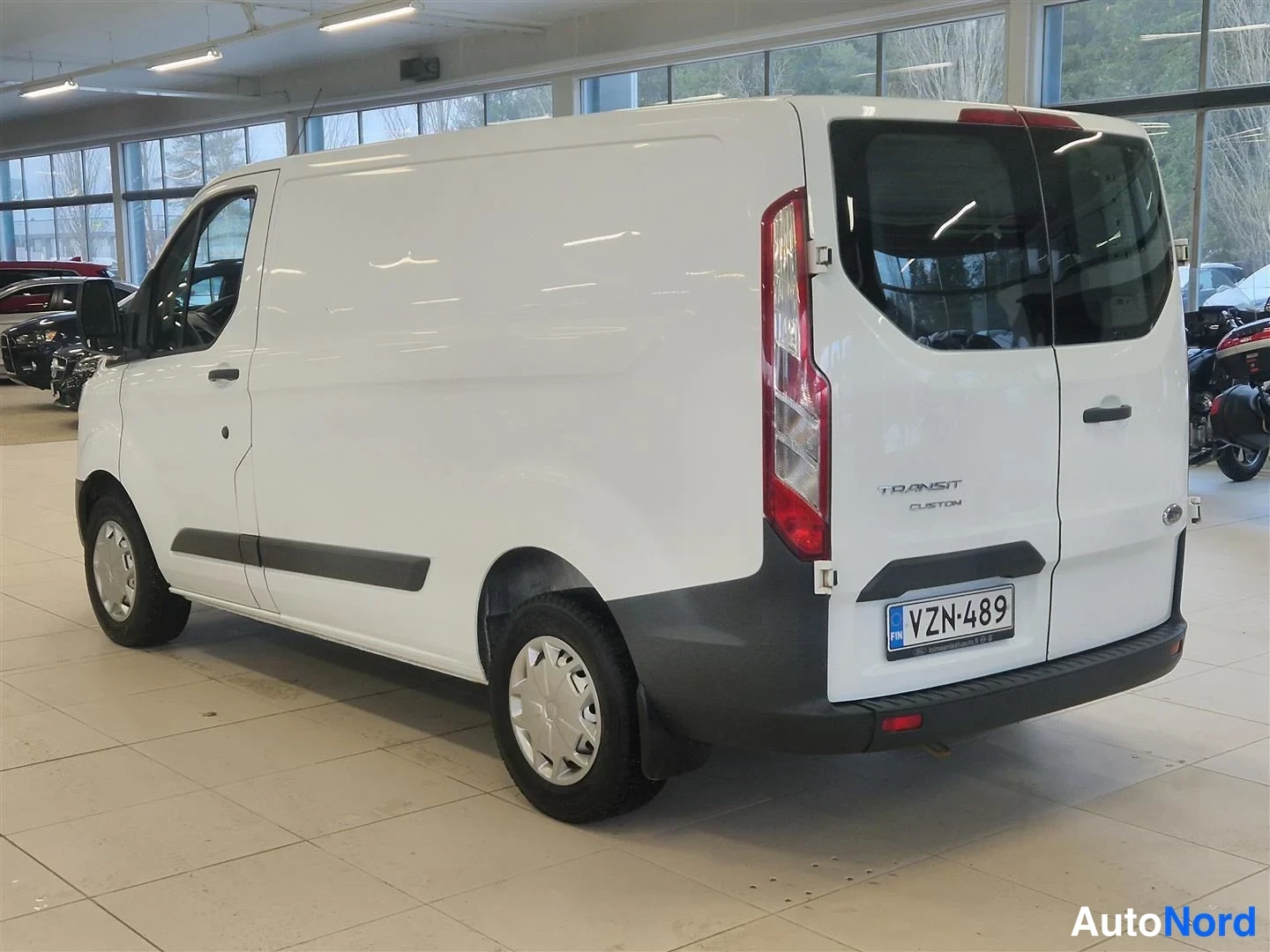 Takaviisto: Valkoinen Ford Transit Custom takaosan ja kyljen näkyvissä takakulmasta, rekisterikilpi.
