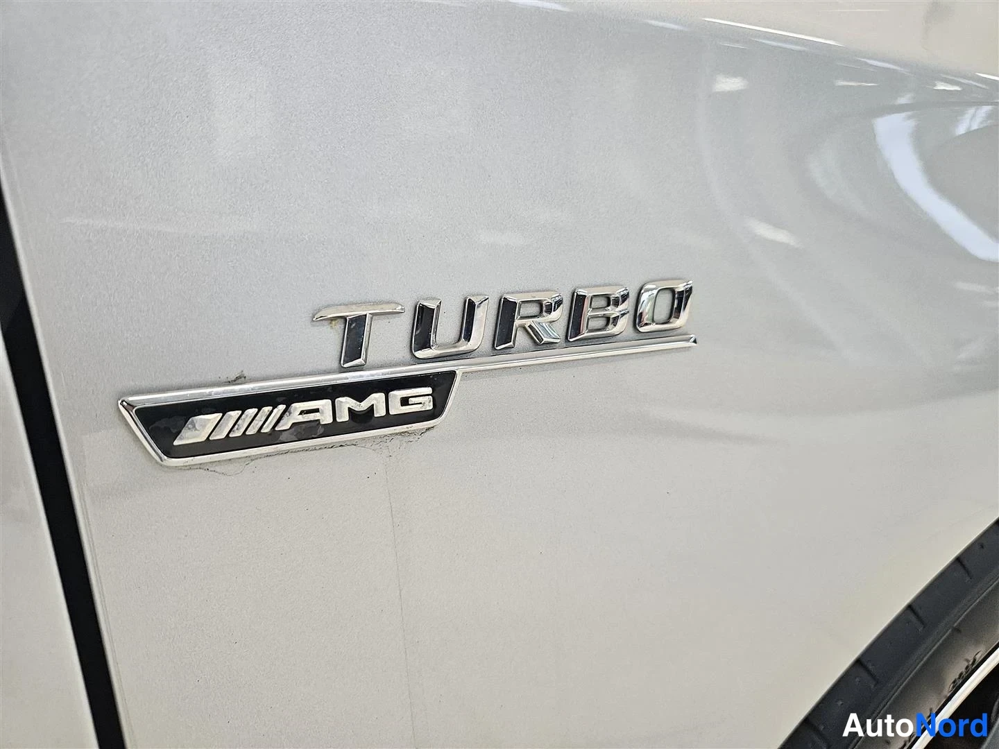 Yksityiskohta: Tarkoitus kuva auton sivupaneelin kromimerkinnästä TURBO AMG hopeanvärisellä pintakäsittelyllä.