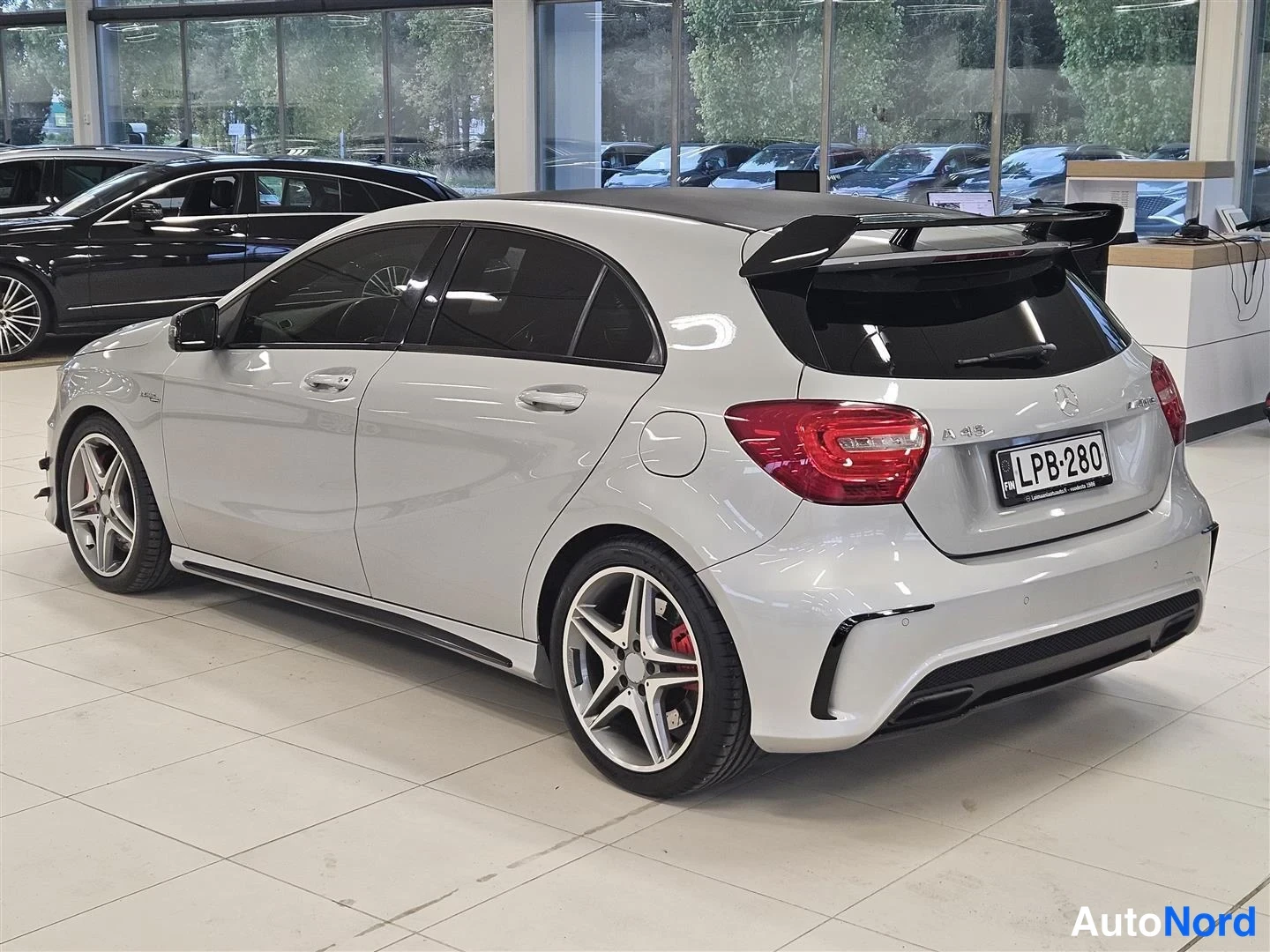 Takaviisto: Hopeanharmaa Mercedes-Benz A 45 AMG viistosti takaa kuvattuna näyttelytilassa, rekisterikilpi.