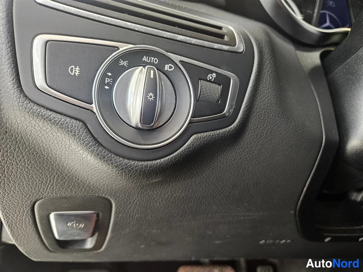 Muu: Sisätilakuva: Mercedes-Benzin ajovalon vipukytkin AUTO-asennossa, jonka ympärillä symbolit mm. sumuvalo ja parkkivalot.