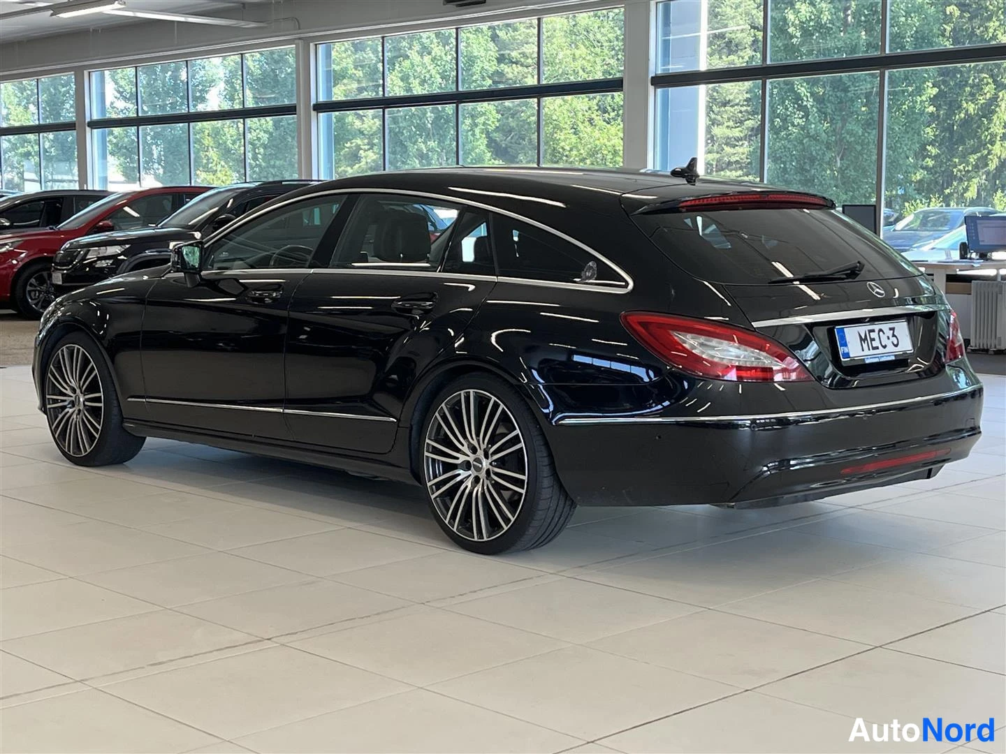 Takaviisto: Mustan Mercedes-Benz CLS -farmariauton takakulma sisätiloissa, rekisterikilpi.
