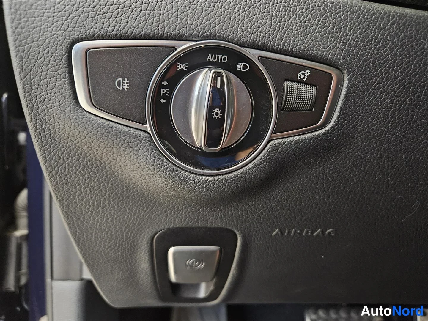 Yksityiskohta: Ohjaamon valokytkin AUTO-asennossa ja lisäpainike, jonka viereen on merkitty AIRBAG.