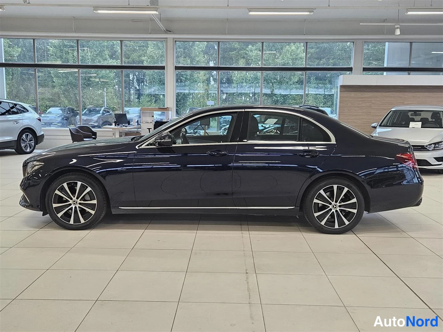 Sivulta: Mercedes-Benz E 300e -sedanin sivuprofiili oikealta katsottuna, tummansininen korimaali ja monihaaravanteet