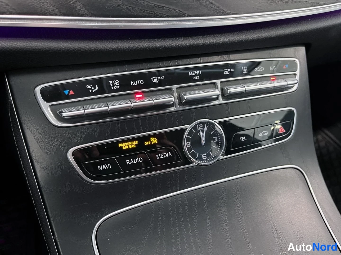 Muu: Keskikonsolin ilmastointipaneeli, jossa on näkyvissä AUTO-, MAX-, MENU REST-, REAR-, A/C-toiminnot sekä NAVI-, RADIO- ja MEDIA-napit, analoginen kello ja PASSen