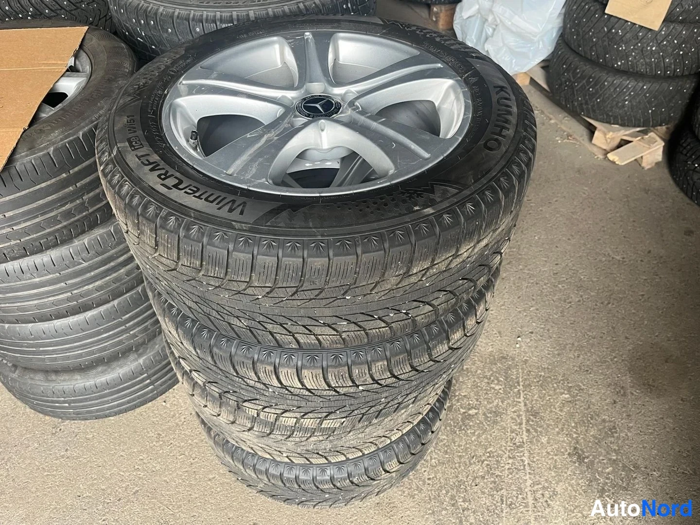 Yksityiskohta: Pino Mercedes-merkityllä alumiinivanteilla varustettuja Kumho WinterCraft WP51 -talvirenkaita varastossa.