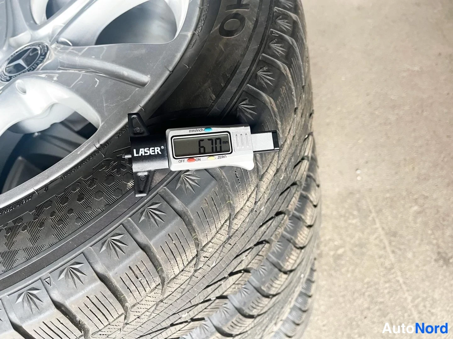 Yksityiskohta: Lasermittari näyttää 6,70 mm:n urasyvyyden talvirenkaassa Mercedes-vanteen alla.