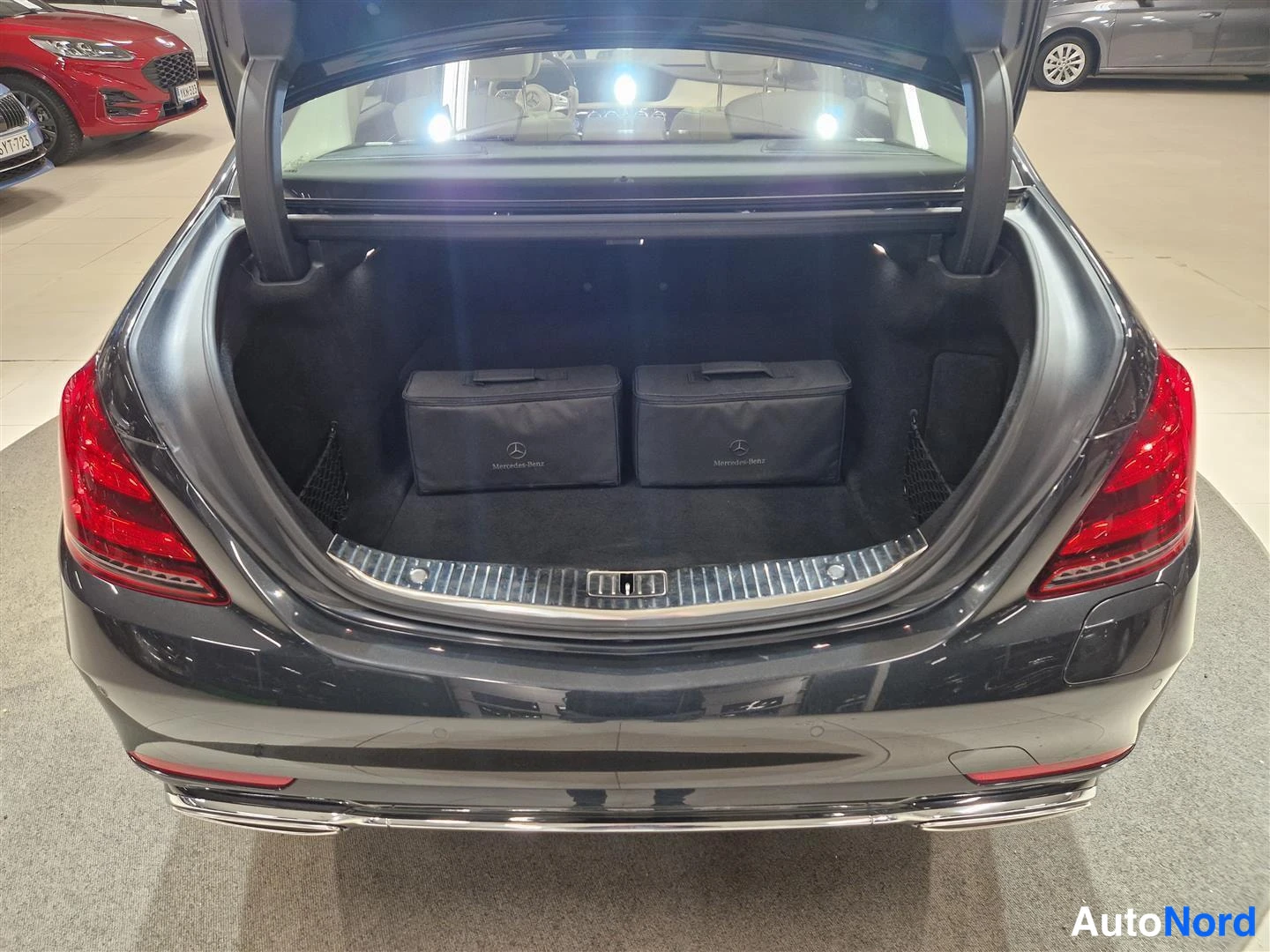 Takaa: Auton takakansi auki näkyy takaa: tumma avaaja-avaimet laukkuja Mercedes-Benz-merkeillä ja kirkas turvalamppu.