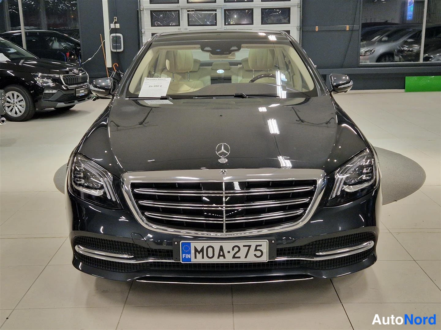 Edestä: Mercedes-Benz S-luokan sedan etupäältä, rekisteri, tumma koripainta, myyntitunnus tuulilasissa.