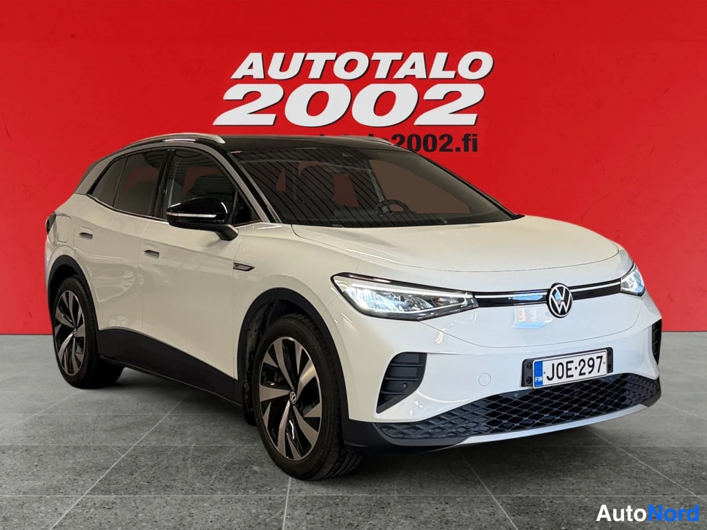 Etuviisto, nokka oikealle: Valkoinen Volkswagen ID.4 etukulmasta, rekisteritunnus, punainen tausta.