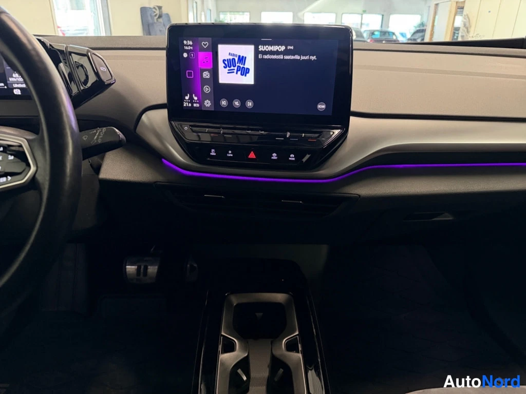 Edestä: Kojelaudan infotainment-näyttö ja keskikonsoli, näytössä radio SUOMIPOP, PURPLE-violetti tunnelmavalaistus