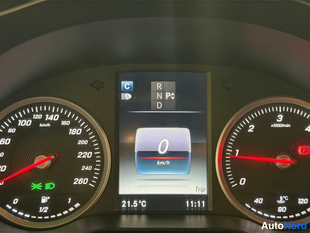 Muu: Mercedes-Benzin mittaristo: nopeusmittari, kierrosmittari ja keskellä näyttö, jossa säätötila P ja nopeus 0 km/h, lämpötila 21,5 °C ja aika 11:11.