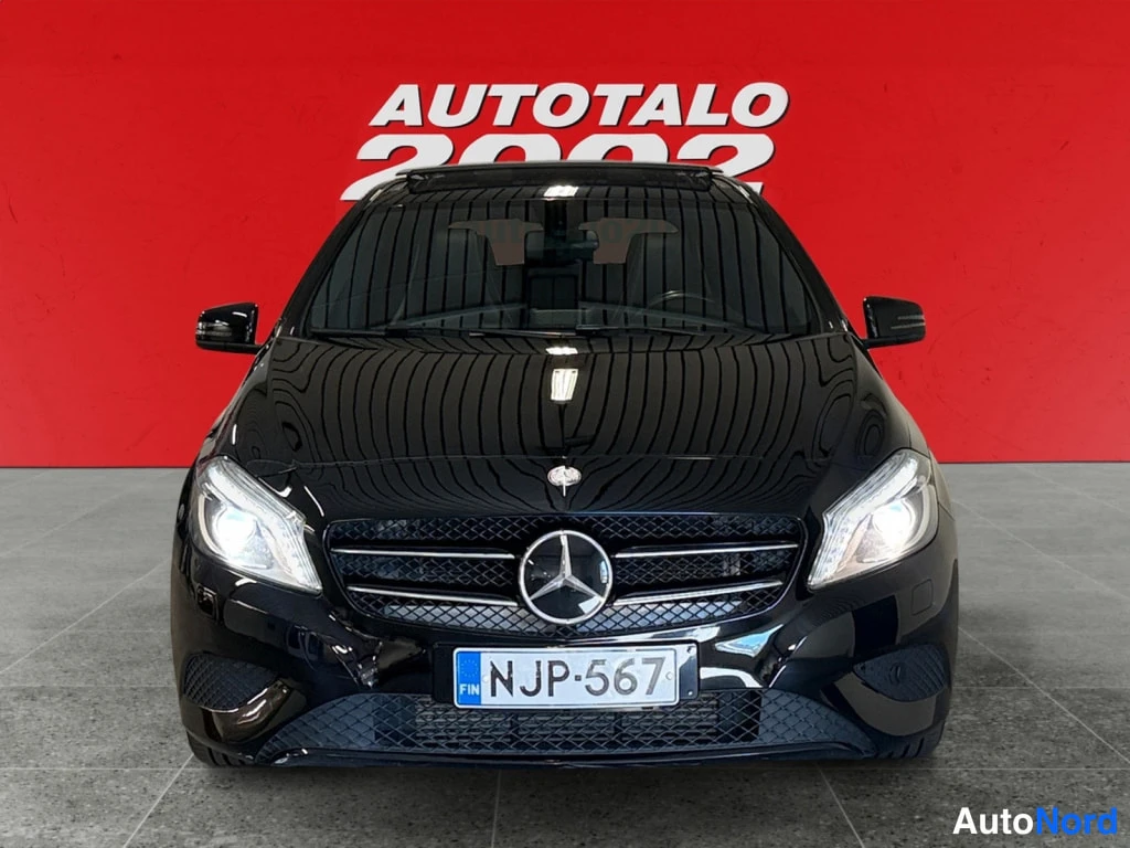 Edestä: Mustan Mercedes-Benz A:n etunäkymä punaisella taustalla, rekisteritunnus.