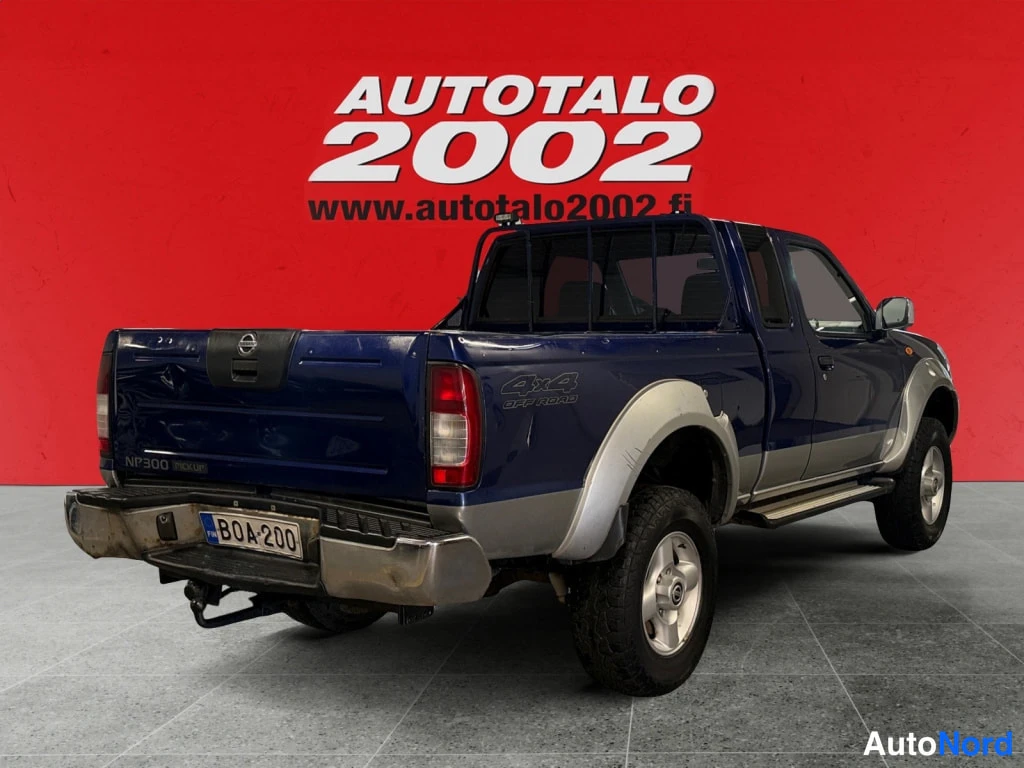 Takaviisto: Tummansininen Nissan NP300 -mallinen avolava-auto takaviistosta vasemmalta, lava auki, takana rekisterikilpi BOA·200 ja lavan asennusrunko.