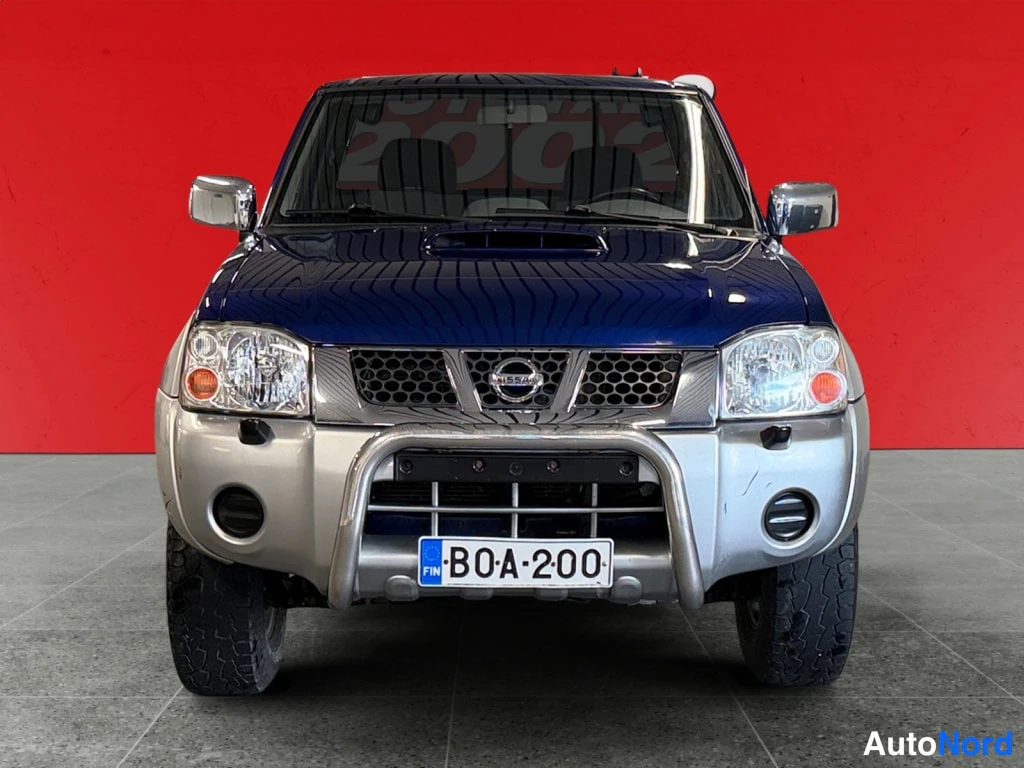 Edestä: Nissan NP300 -mallin suora etukuva; Nissan-merkki säleikkössä ja suojakaari edessä, rekisterikilpi.