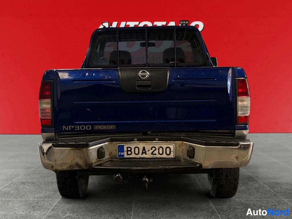 Takaa: Nissan NP300 -mallin suora takakuva; lavan takaosa ja takavalot, takapuskurin metalliosa ruostetta, rekisterikilpi.