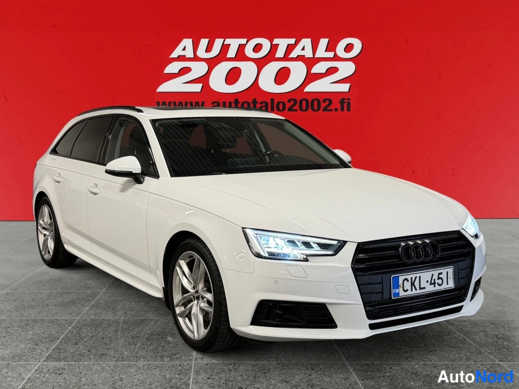 Etuviisto, nokka oikealle: Valkoinen Audi A4 -farmari etuviistosta vasemmalle katsottuna punaisella taustalla.