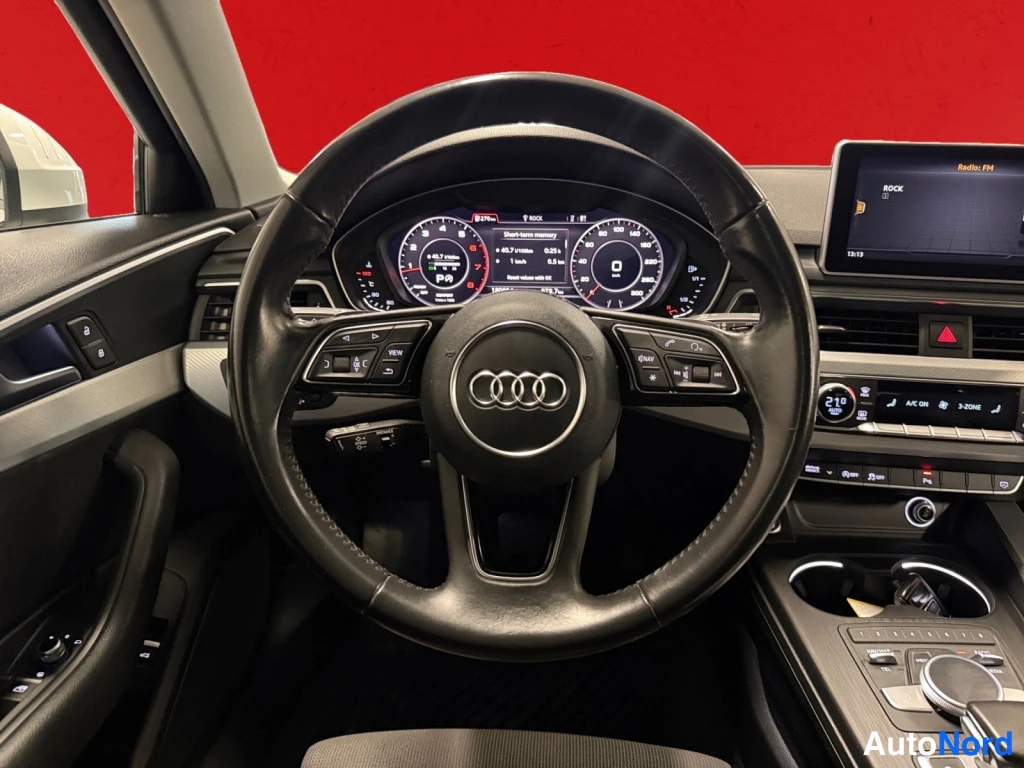 Yksityiskohta: Ohjaamo näkyvissä: Audi-ohjauspyörä, digitaalinen mittaristo ja keskinäytöllä radiokanava ROCK.