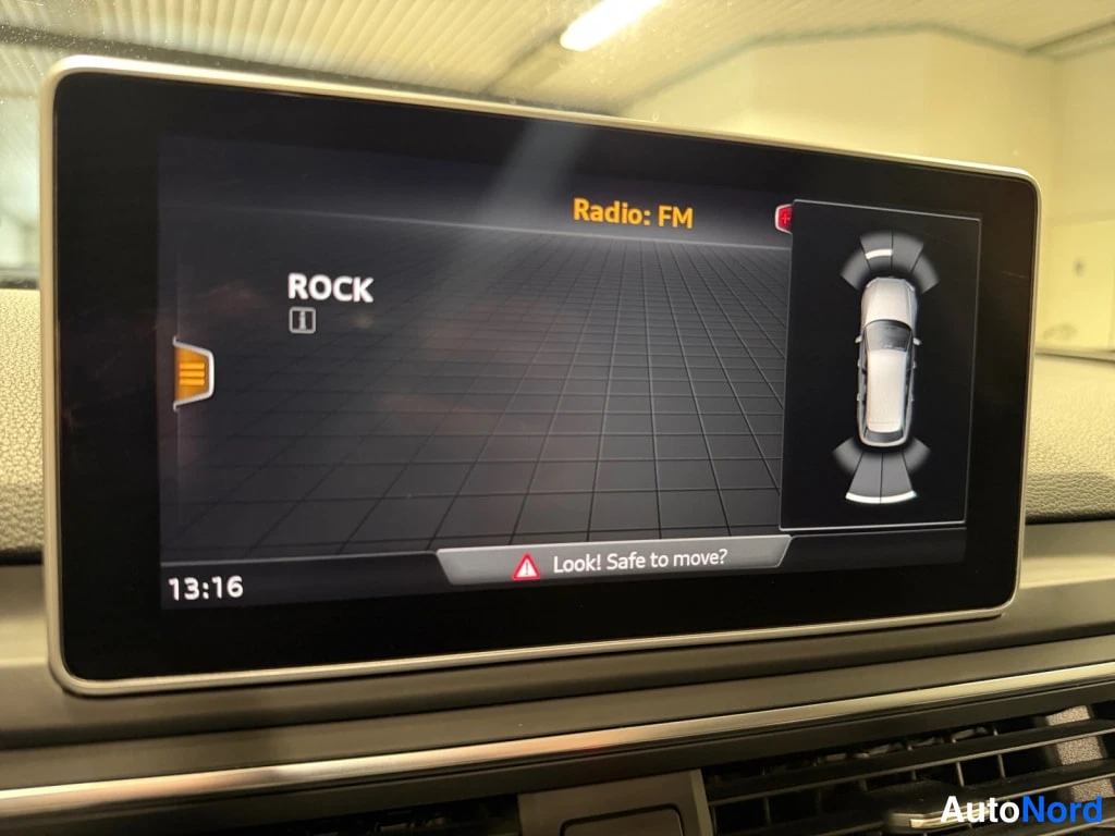 Muu: Kojelaudan keskinäyttö näyttää radion FM-kanavan ROCK sekä pysäköintitutkan ajoneuvon kuvan, kello 13:16.
