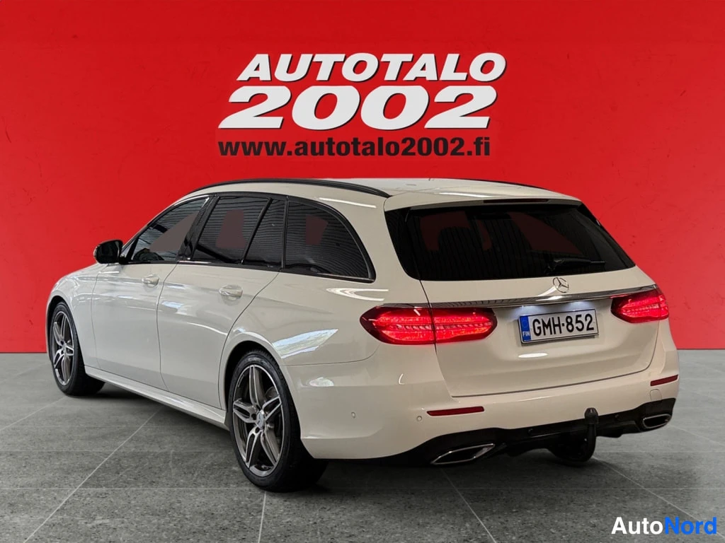 Takaviisto: Mercedes-Benz E -farmari takaa viistosti vasemmalta, valkoinen kori, punaiset takavalot ja rekisteri.