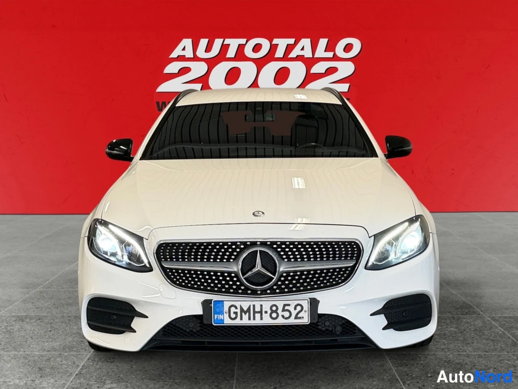 Edestä: Mercedes-Benz E -farmari suoraan edestä, valkoinen kori, tumma pystysäleikkö ja rekisteri.