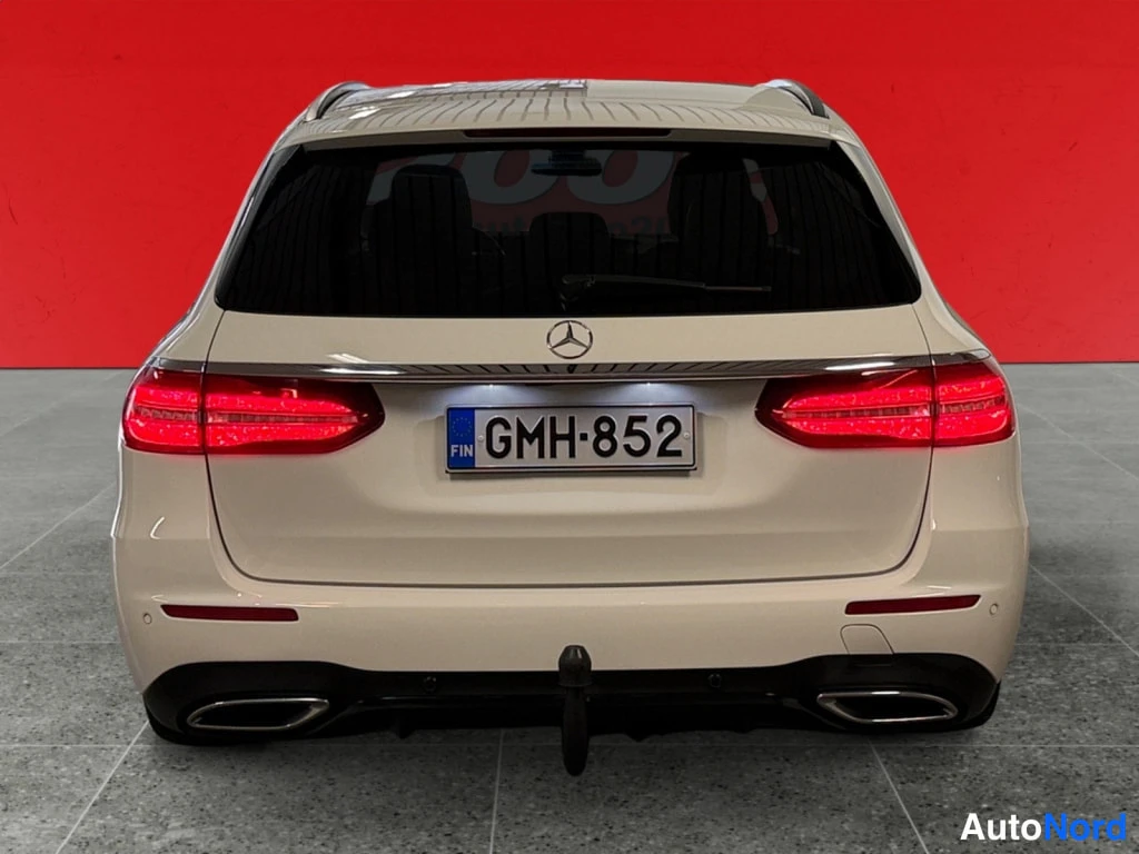 Takaa: Mercedes-Benz E -farmarin takaosa suoraan takaa, punaiset takavalot, rekisteri ja vetokoukun pallo.