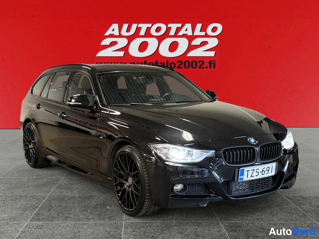 Etuviisto, nokka oikealle: Musta BMW-farmariauto etuviistosta oikealta, rekisteritunnus